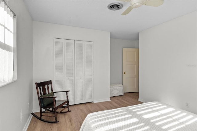 bedroom with baseboards, visible vents, wood finished floors, and a closet