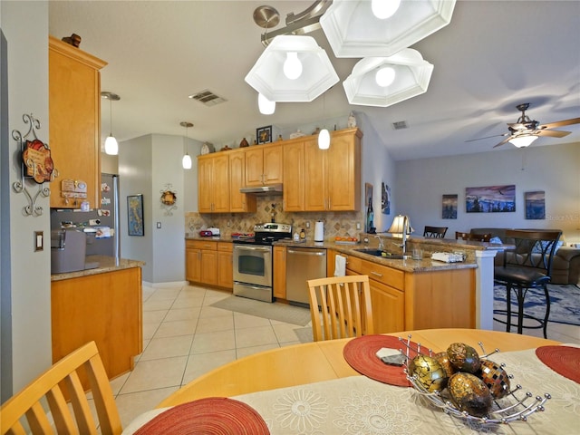 kitchen with sink, appliances with stainless steel finishes, hanging light fixtures, light tile patterned flooring, and kitchen peninsula