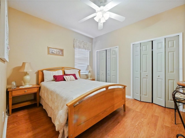 bedroom with hardwood / wood-style flooring, ceiling fan, and multiple closets