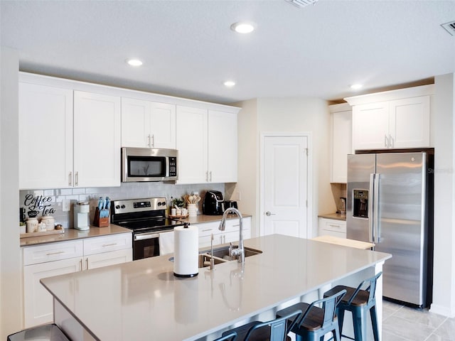 kitchen with appliances with stainless steel finishes, light tile patterned floors, and white cabinets