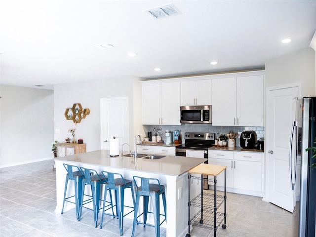 kitchen with white cabinetry, sink, an island with sink, and appliances with stainless steel finishes