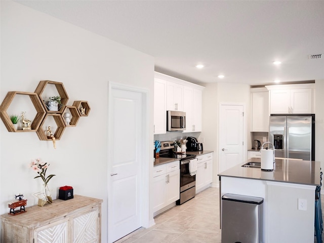 kitchen featuring sink, appliances with stainless steel finishes, a kitchen island with sink, white cabinets, and light tile patterned flooring