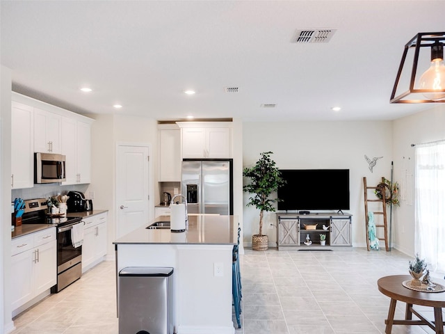 kitchen featuring white cabinetry, appliances with stainless steel finishes, a kitchen island with sink, and sink