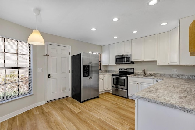 kitchen with pendant lighting, sink, appliances with stainless steel finishes, light hardwood / wood-style floors, and white cabinets