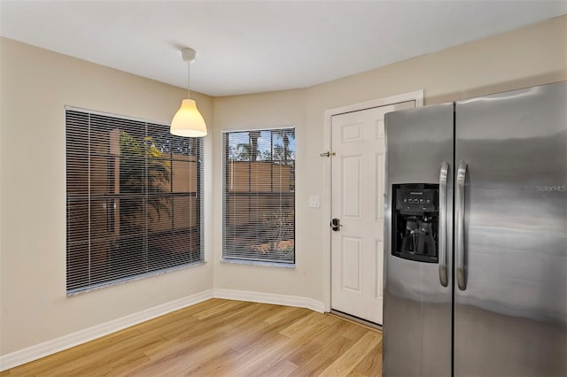 kitchen featuring stainless steel fridge, decorative light fixtures, and light wood-type flooring