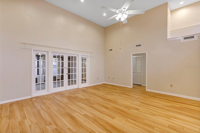 spare room with french doors, ceiling fan, light wood-type flooring, and a high ceiling