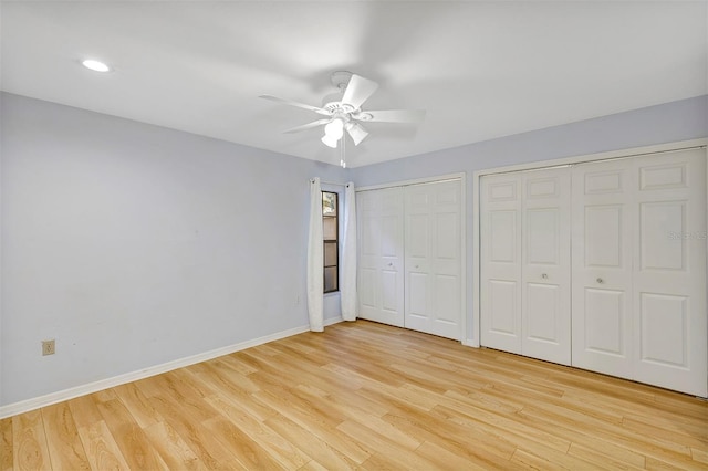 unfurnished bedroom with two closets, ceiling fan, and light hardwood / wood-style flooring