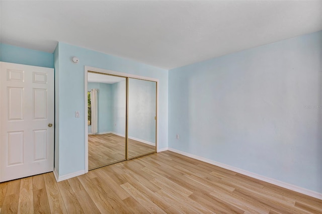 unfurnished bedroom featuring light hardwood / wood-style flooring and a closet