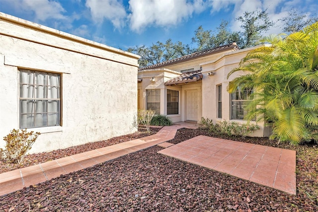 view of exterior entry with a patio