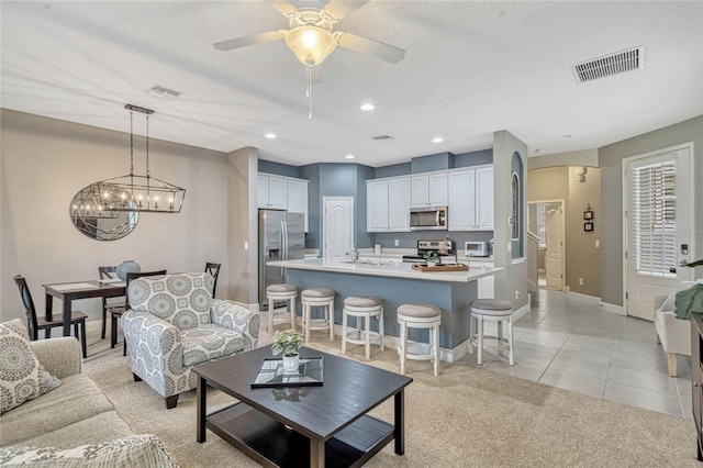 living room featuring sink, light tile patterned floors, and ceiling fan