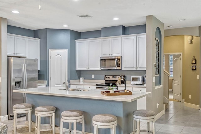 kitchen with appliances with stainless steel finishes, a center island with sink, and white cabinets