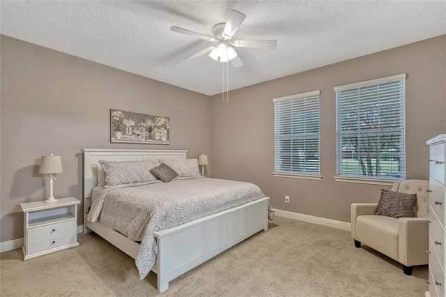 bedroom featuring light carpet, a textured ceiling, and ceiling fan