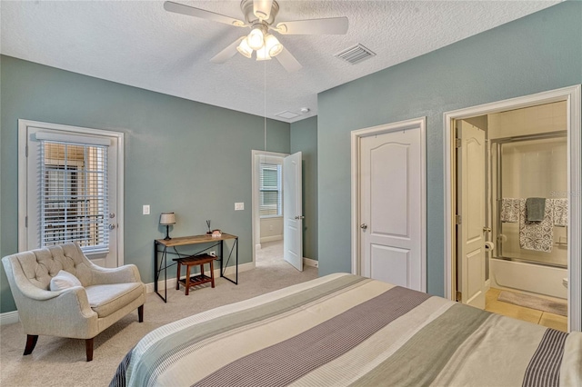 bedroom featuring ceiling fan, ensuite bath, light carpet, and a textured ceiling