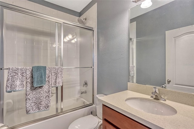 full bathroom featuring vanity, combined bath / shower with glass door, and toilet