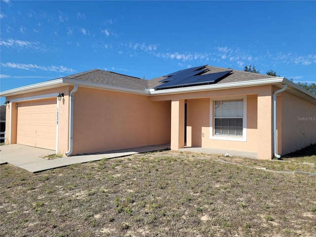 single story home featuring a garage, a front lawn, and solar panels