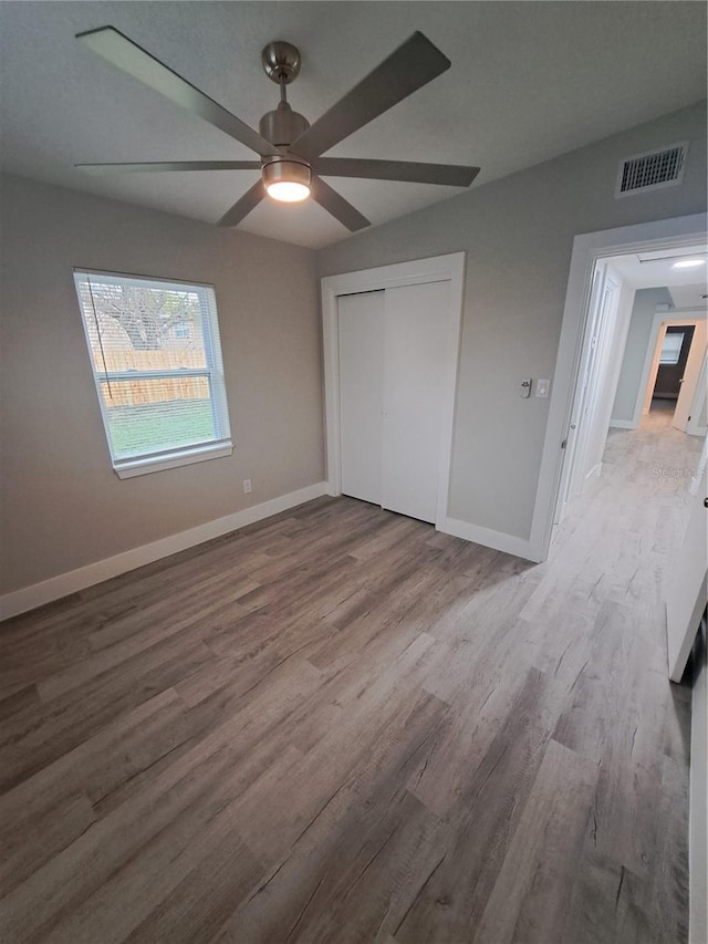 unfurnished bedroom with light hardwood / wood-style floors, a closet, and ceiling fan