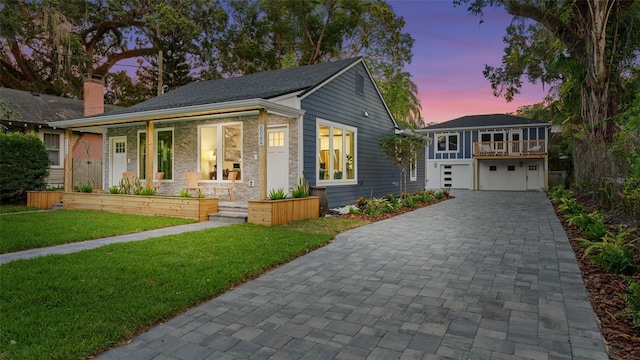 view of front of property with a garage, covered porch, and a lawn