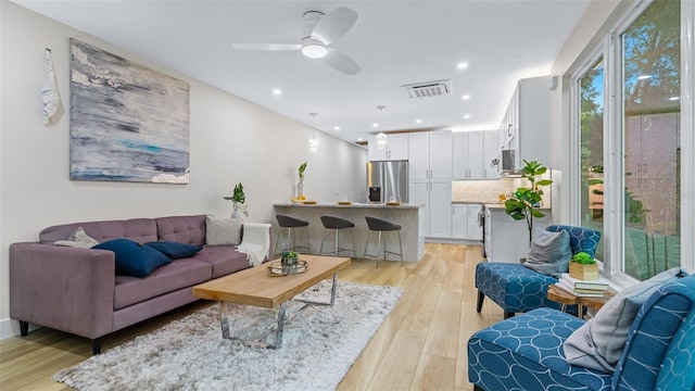 living room featuring ceiling fan, a healthy amount of sunlight, and light hardwood / wood-style floors