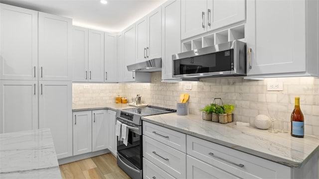 kitchen with white cabinetry, stainless steel appliances, light stone countertops, and decorative backsplash