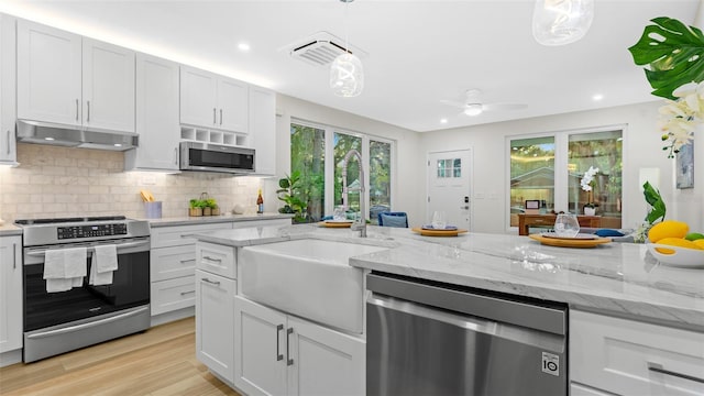 kitchen featuring stainless steel appliances, decorative light fixtures, and white cabinets