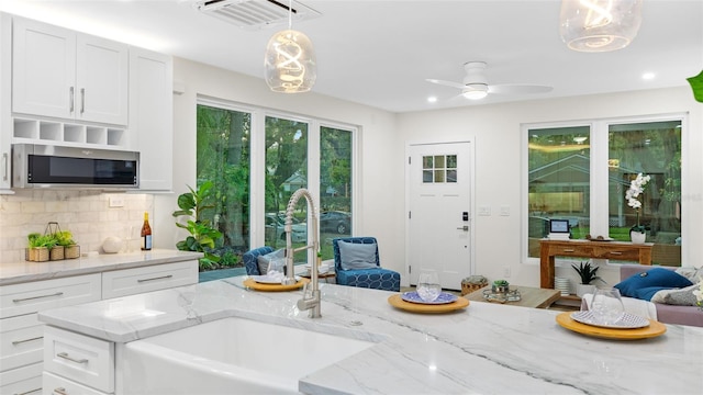 kitchen with hanging light fixtures, white cabinetry, sink, and tasteful backsplash