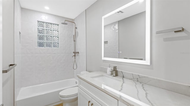 full bathroom with tiled shower / bath, vanity, and toilet