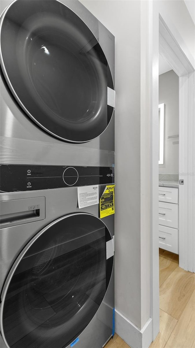 washroom featuring stacked washer and clothes dryer and light hardwood / wood-style floors