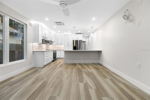 kitchen featuring stainless steel appliances, hanging light fixtures, white cabinets, and light wood-type flooring