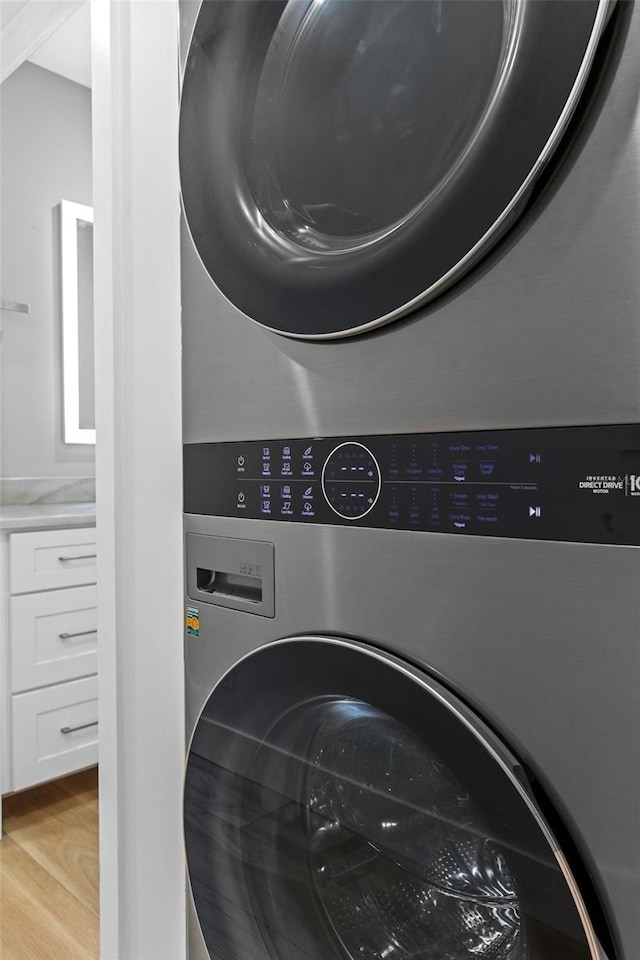 laundry area featuring stacked washer and dryer and light hardwood / wood-style floors