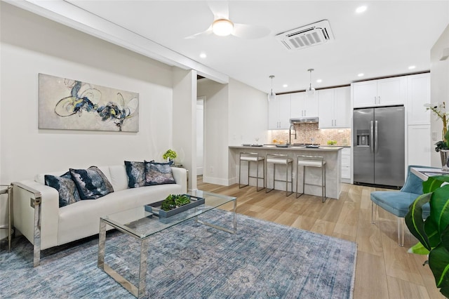 living room featuring ceiling fan, sink, and light hardwood / wood-style floors