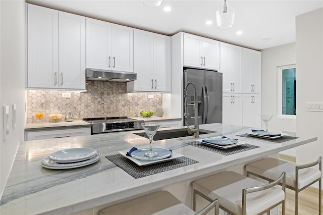 kitchen featuring white cabinetry, appliances with stainless steel finishes, light stone countertops, and hanging light fixtures