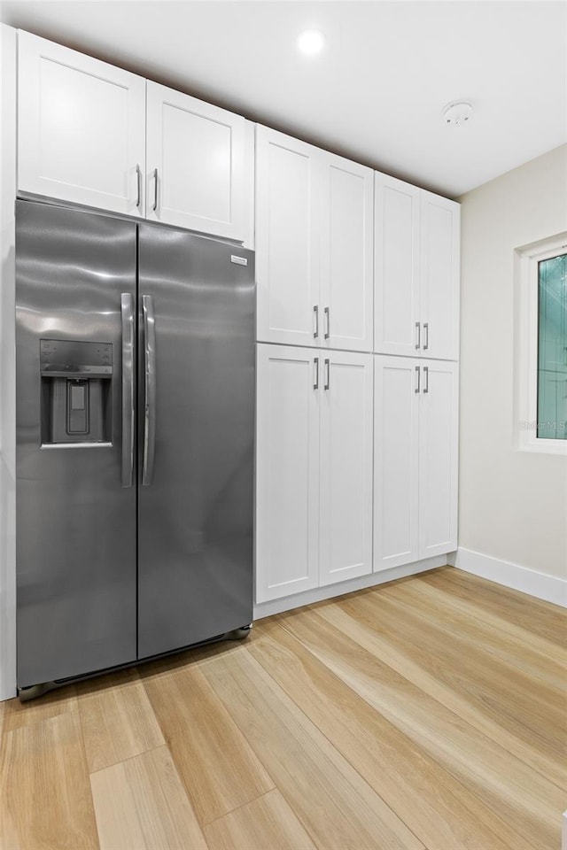 kitchen with light hardwood / wood-style flooring, white cabinets, and stainless steel fridge with ice dispenser