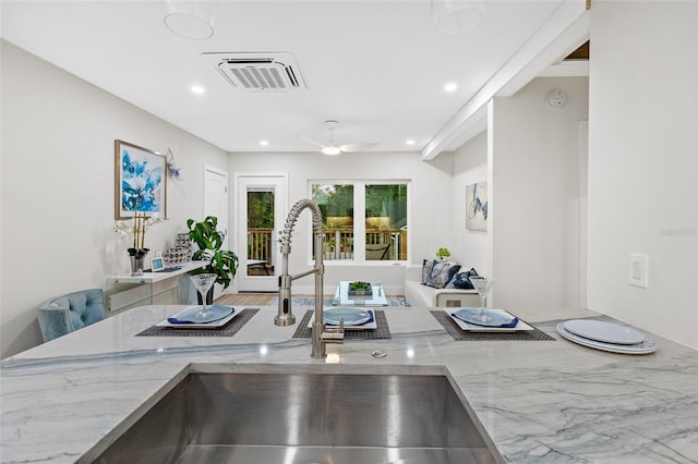 kitchen with light stone counters, sink, and ceiling fan