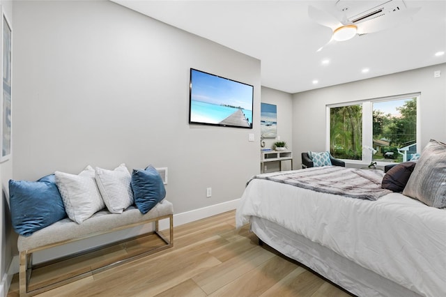 bedroom featuring ceiling fan, a wall mounted AC, and light wood-type flooring