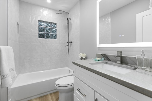 full bathroom featuring tiled shower / bath combo, vanity, wood-type flooring, and toilet