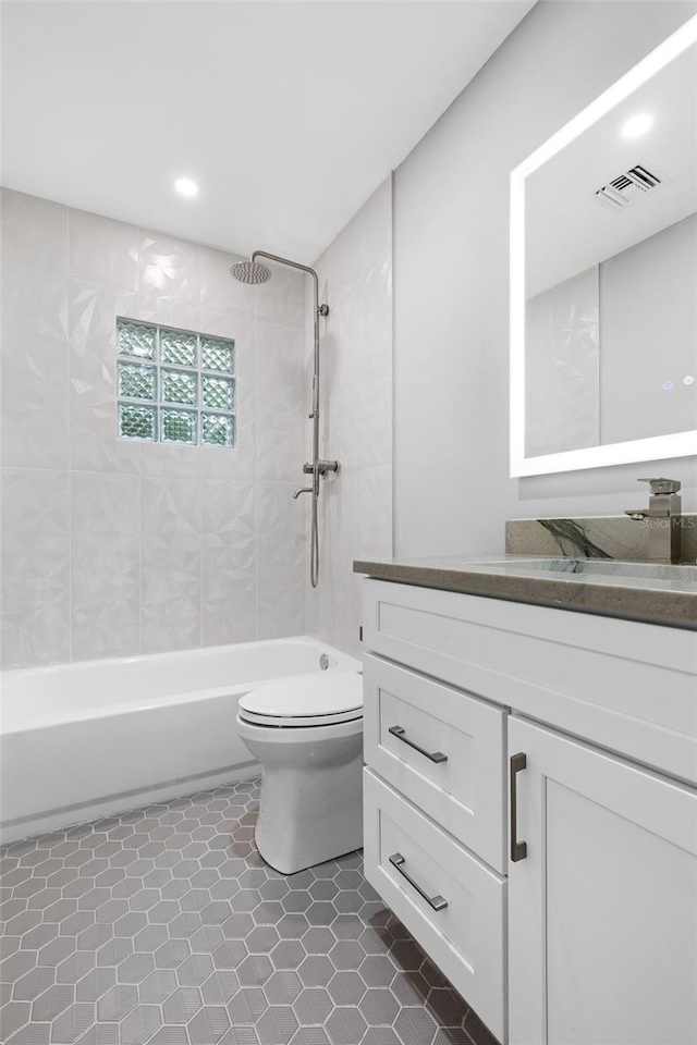 full bathroom featuring vanity, tile patterned flooring, tiled shower / bath combo, and toilet