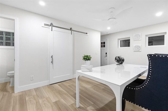 dining area with light hardwood / wood-style flooring and a barn door