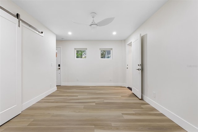 corridor featuring a barn door and light hardwood / wood-style floors