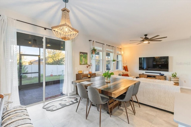 dining space featuring a healthy amount of sunlight, ceiling fan with notable chandelier, and light tile patterned floors