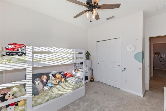 bedroom featuring light colored carpet, a closet, and ceiling fan