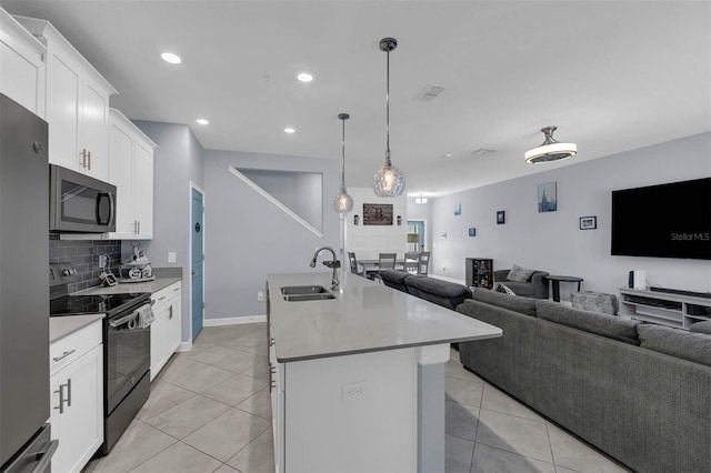 kitchen featuring sink, appliances with stainless steel finishes, a kitchen island with sink, white cabinets, and decorative backsplash