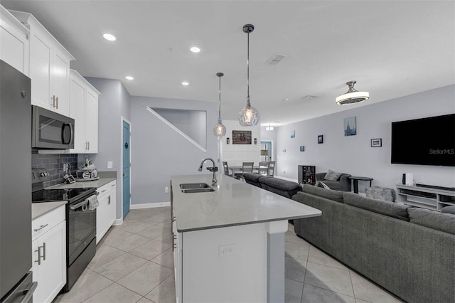 kitchen with a kitchen island with sink, black electric range, a sink, tasteful backsplash, and open floor plan