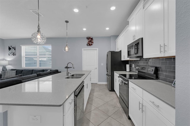 kitchen with a center island with sink, decorative backsplash, appliances with stainless steel finishes, white cabinets, and a sink