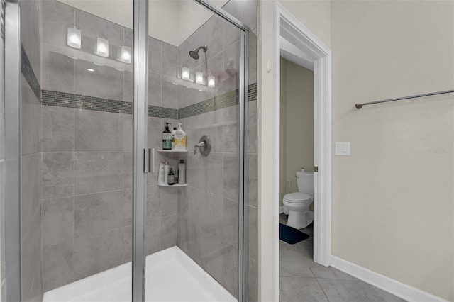 bathroom with baseboards, toilet, a shower stall, and tile patterned flooring