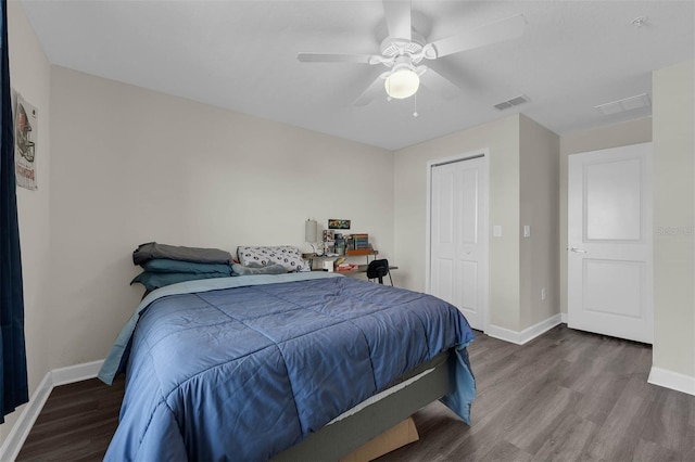 bedroom with a ceiling fan, wood finished floors, visible vents, baseboards, and a closet