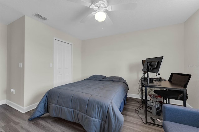 bedroom featuring visible vents, a ceiling fan, wood finished floors, a closet, and baseboards