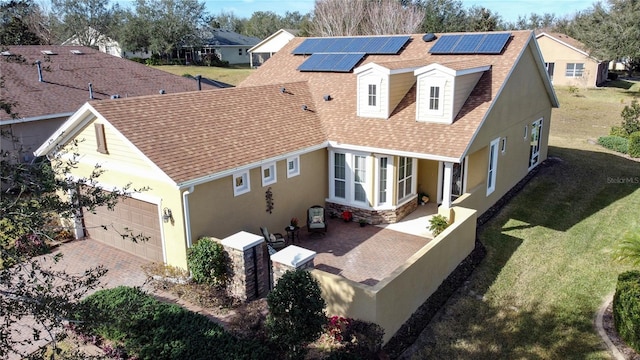 back of property featuring a garage, a yard, and solar panels