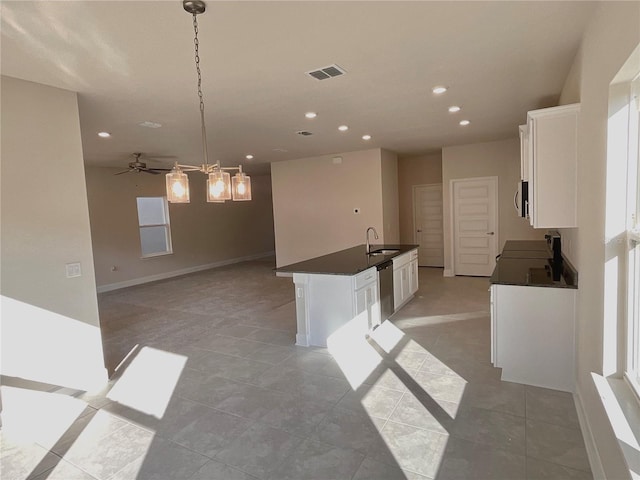 kitchen with pendant lighting, sink, white cabinets, a kitchen island with sink, and stainless steel appliances