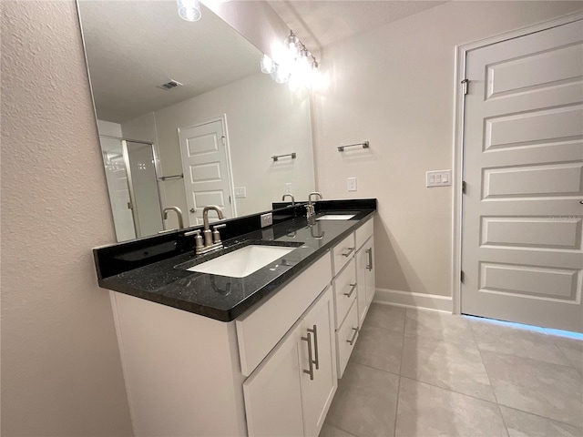 bathroom with a shower with door, vanity, and tile patterned floors