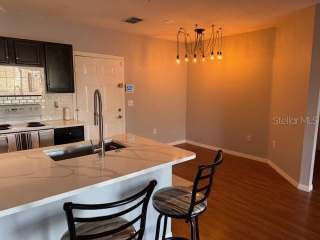 kitchen featuring sink, a breakfast bar, hanging light fixtures, light stone counters, and white electric stove